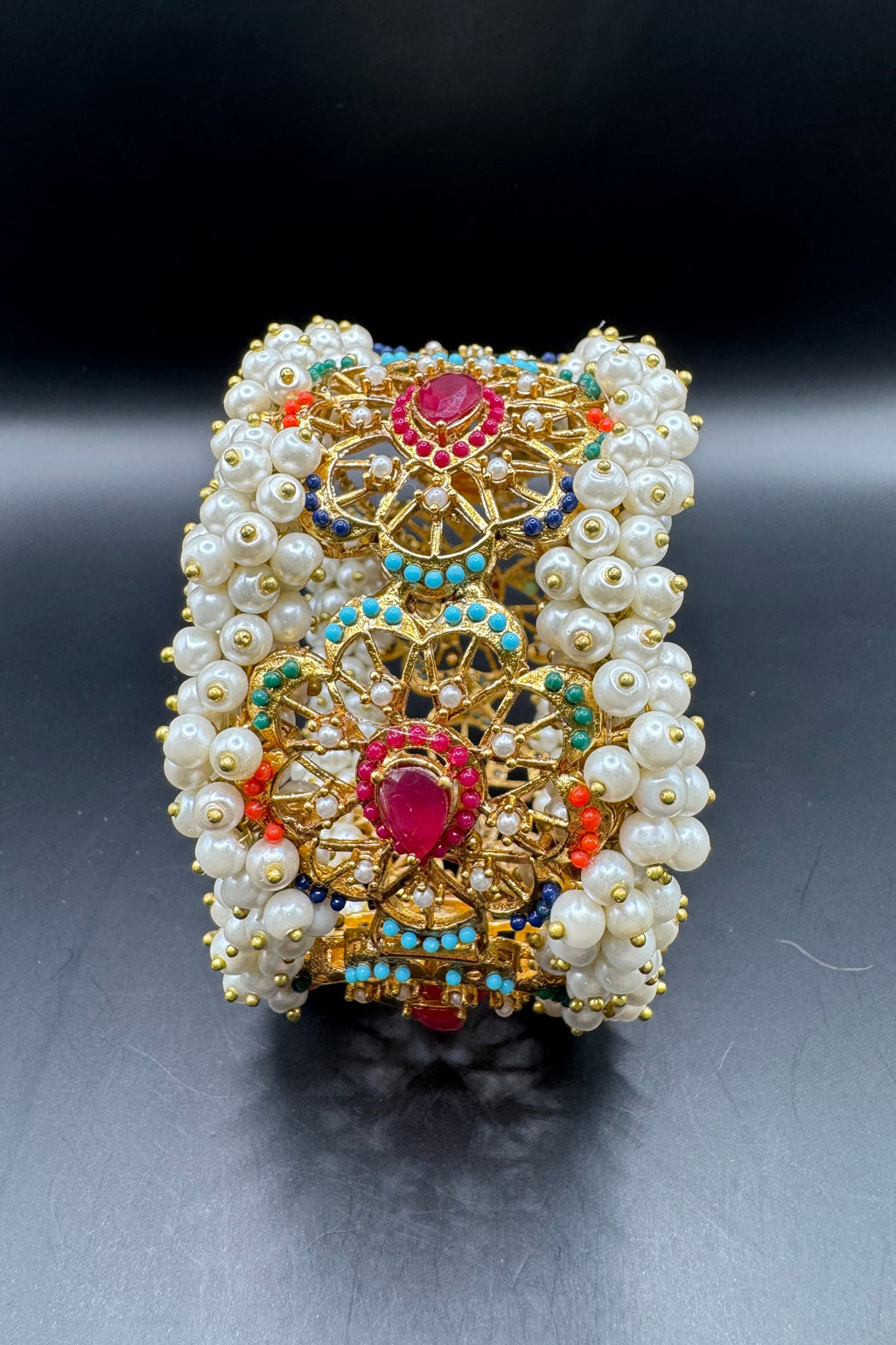 Decorative bracelet with pearls and colorful stones on a dark background
