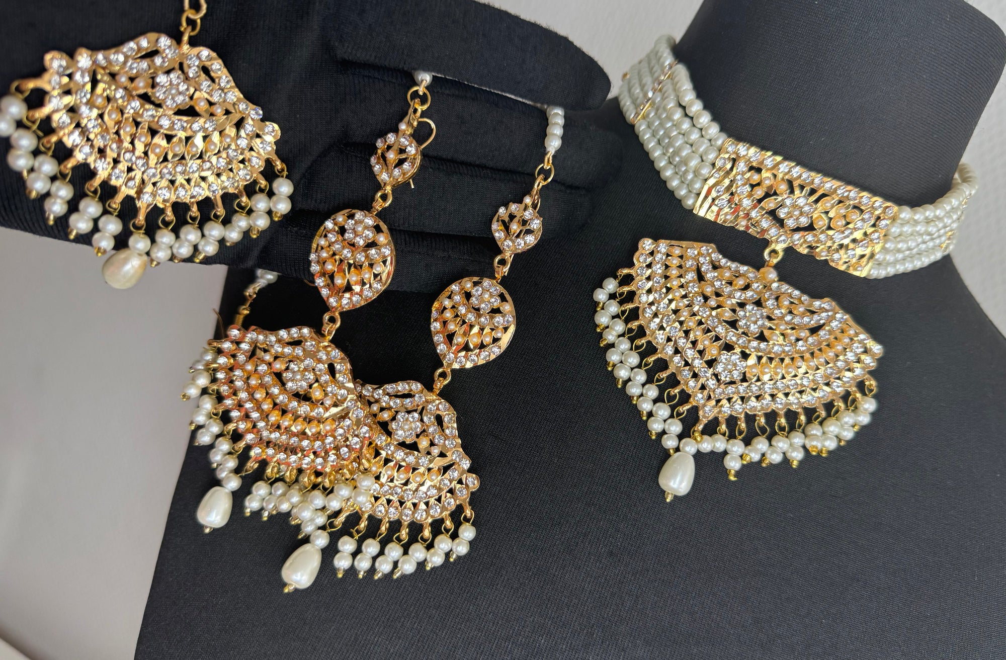 Set of gold and pearl jewelry on a black mannequin