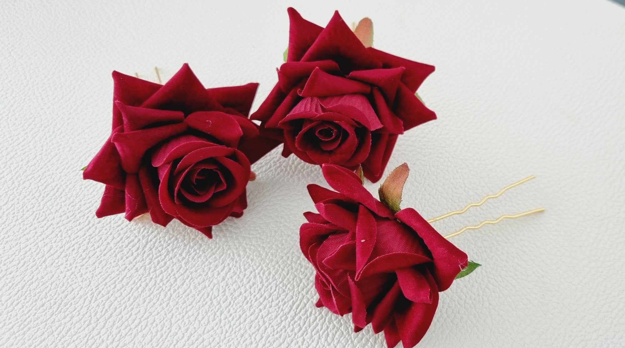 Red rose hairpins on a white surface